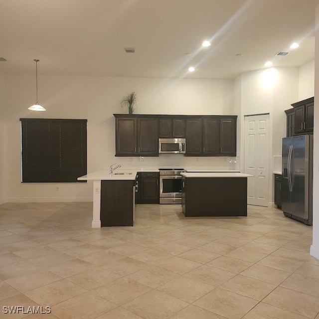 kitchen with pendant lighting, an island with sink, sink, stainless steel appliances, and a towering ceiling