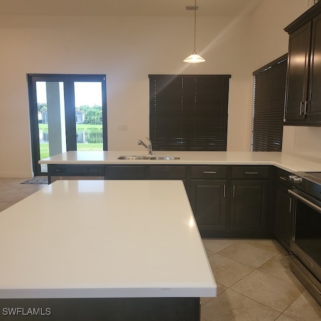 kitchen featuring electric range, sink, hanging light fixtures, a kitchen island, and light tile patterned floors