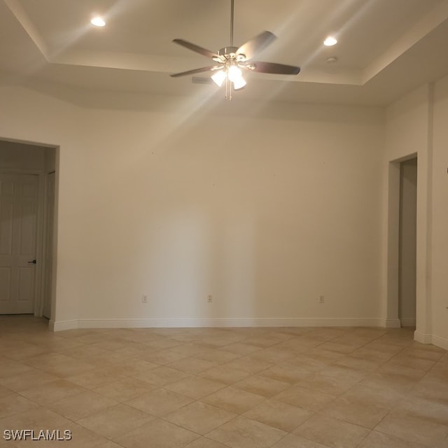 spare room with a tray ceiling and ceiling fan