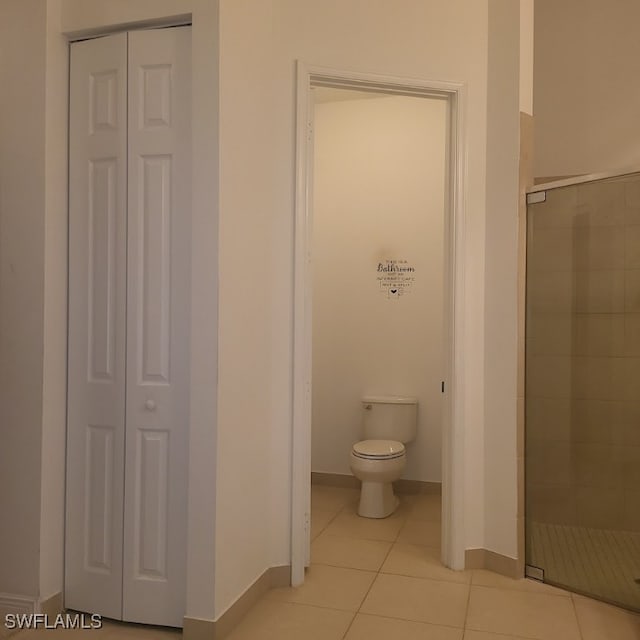 bathroom with a shower with door, toilet, and tile patterned floors