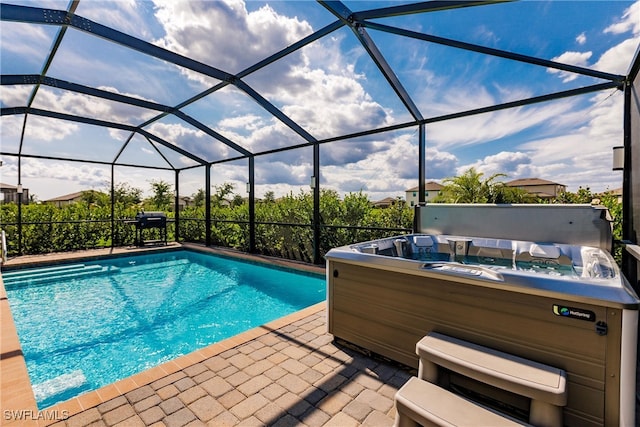 view of swimming pool featuring glass enclosure, a hot tub, and a patio