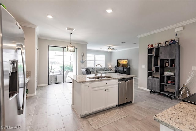 kitchen with white cabinets, pendant lighting, stainless steel appliances, a kitchen island with sink, and sink