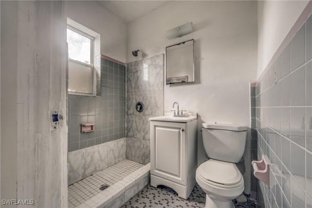 bathroom featuring tile patterned flooring, vanity, tiled shower, and toilet