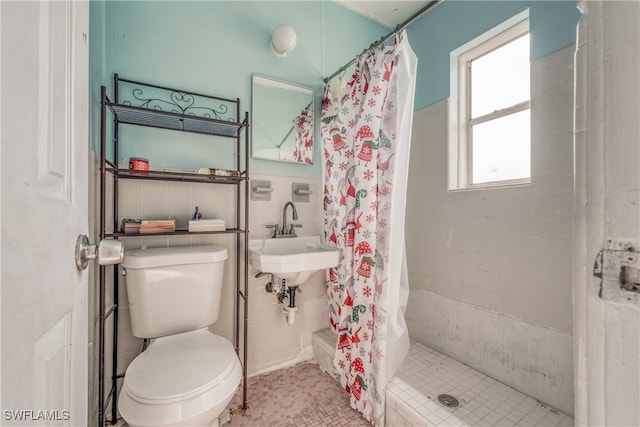 bathroom with sink, walk in shower, toilet, and tile walls