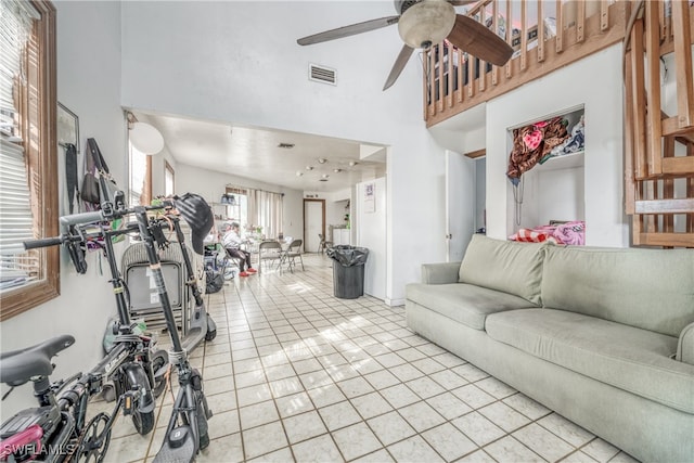 living room with ceiling fan, light tile patterned floors, and a high ceiling