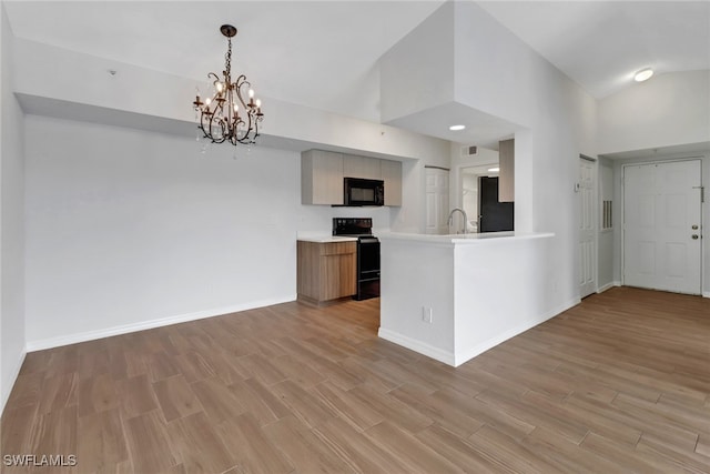 kitchen featuring black appliances, high vaulted ceiling, an inviting chandelier, light hardwood / wood-style floors, and kitchen peninsula