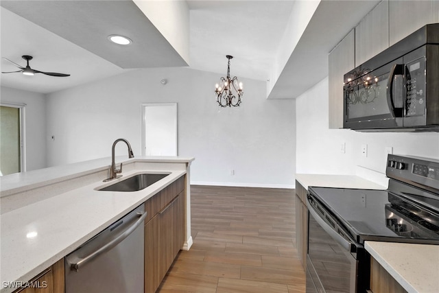 kitchen featuring sink, black appliances, hanging light fixtures, lofted ceiling, and light wood-type flooring