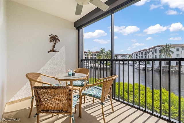 sunroom / solarium with ceiling fan and a water view