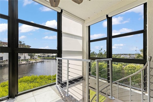 unfurnished sunroom with ceiling fan, a water view, and a wealth of natural light