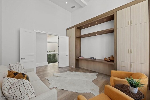 living area featuring light wood-style flooring, a high ceiling, visible vents, and recessed lighting