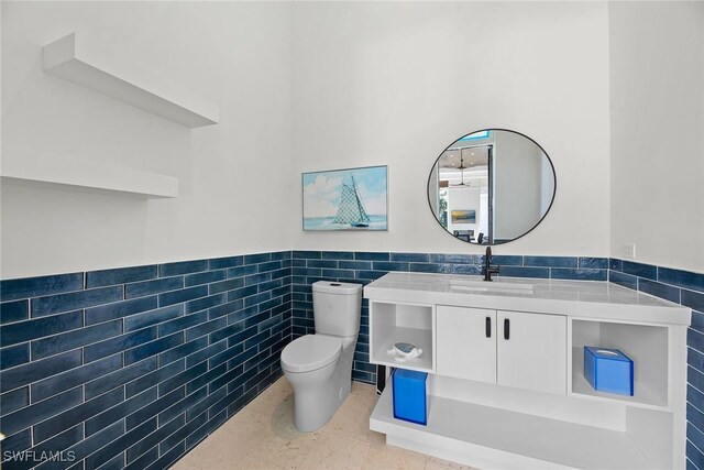 bathroom featuring toilet, vanity, tile walls, wainscoting, and tile patterned floors