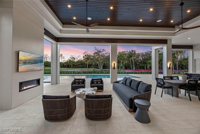 patio terrace at dusk with outdoor dining area, an outdoor pool, an outdoor living space with a fireplace, and ceiling fan