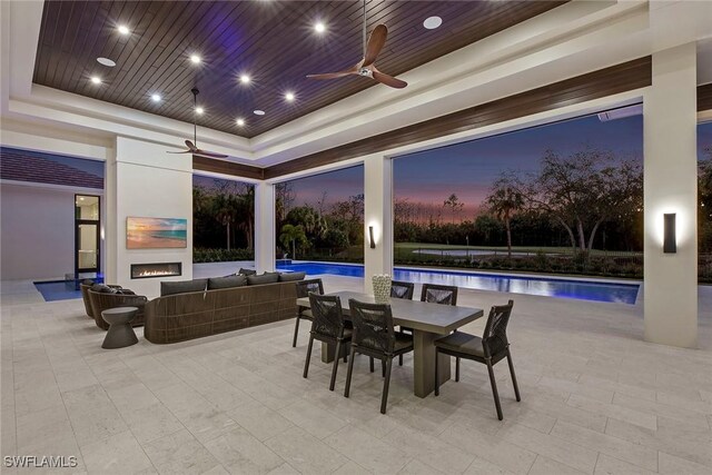 patio terrace at dusk featuring an outdoor pool, ceiling fan, and an outdoor living space