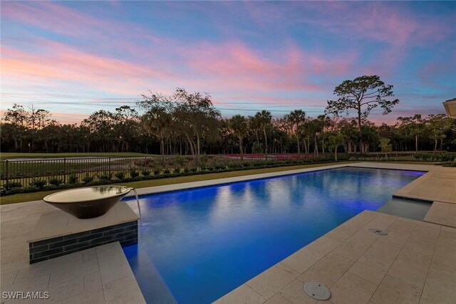 pool at dusk featuring fence, a fenced in pool, and a patio