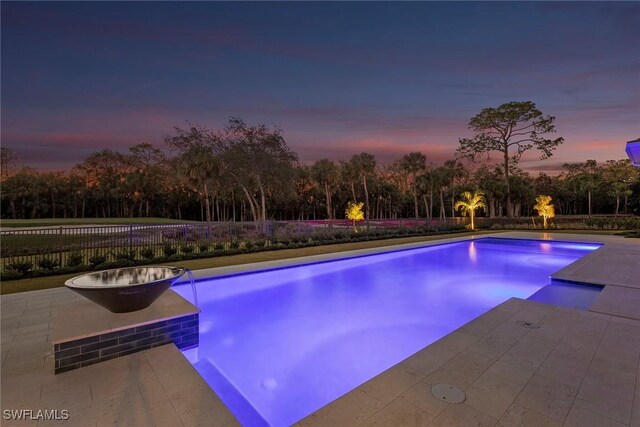 pool at dusk featuring a fenced in pool, a patio area, and fence