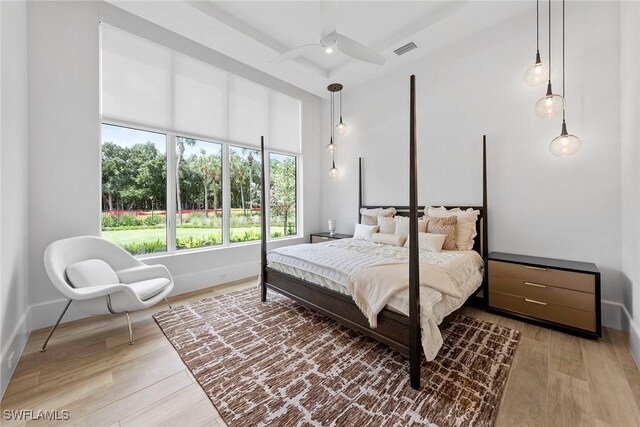 bedroom with a high ceiling, wood finished floors, visible vents, and baseboards