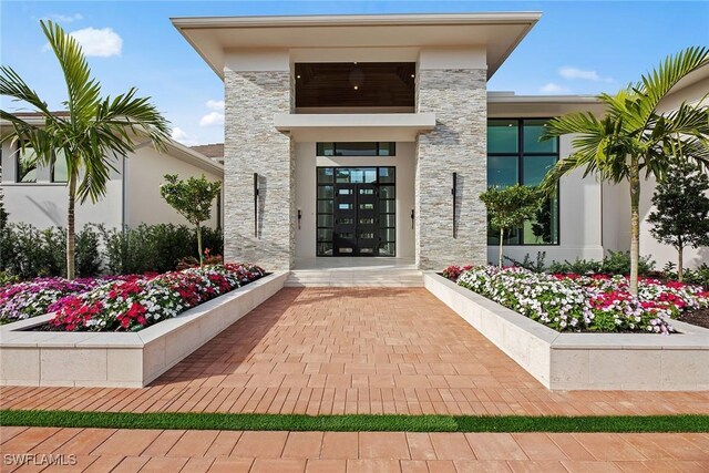 entrance to property featuring stone siding, french doors, and stucco siding