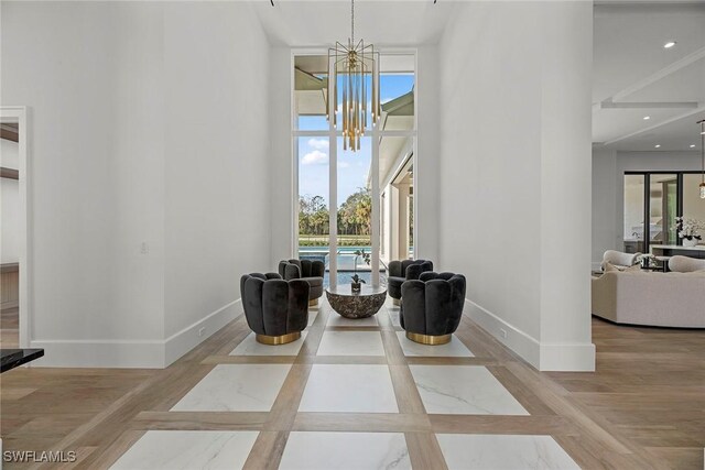 sitting room featuring expansive windows, a high ceiling, baseboards, and an inviting chandelier