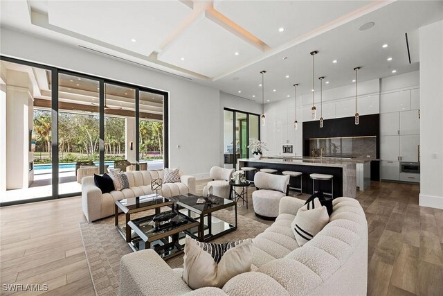 living room with a high ceiling, coffered ceiling, light wood-style flooring, and recessed lighting