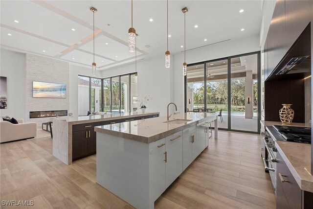 kitchen with a spacious island, pendant lighting, white cabinets, and a sink