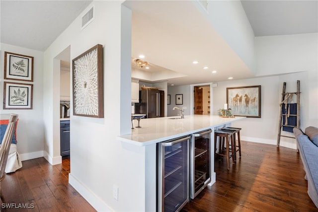 kitchen with a kitchen breakfast bar, stainless steel refrigerator, dark wood-type flooring, and beverage cooler