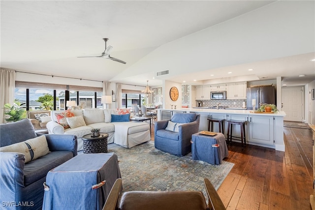 living room with vaulted ceiling, dark hardwood / wood-style flooring, ceiling fan with notable chandelier, and sink