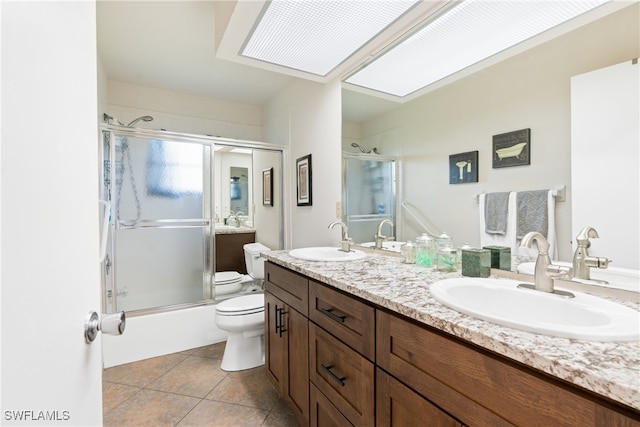 full bathroom with toilet, tile patterned flooring, bath / shower combo with glass door, vanity, and a skylight