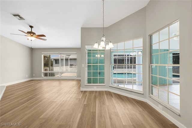 unfurnished dining area featuring wood-type flooring and ceiling fan with notable chandelier