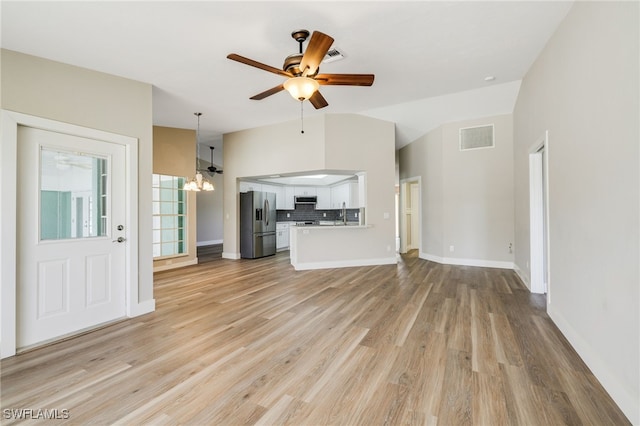 unfurnished living room with light hardwood / wood-style floors, lofted ceiling, and ceiling fan with notable chandelier