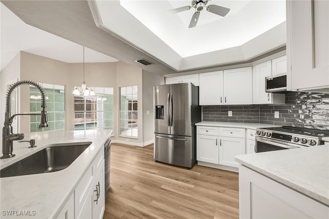 kitchen featuring sink, light wood-type flooring, white cabinetry, appliances with stainless steel finishes, and tasteful backsplash