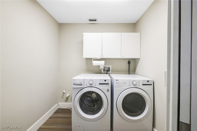 washroom featuring independent washer and dryer, cabinets, and dark hardwood / wood-style flooring