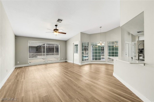 unfurnished living room featuring ceiling fan with notable chandelier and light hardwood / wood-style floors