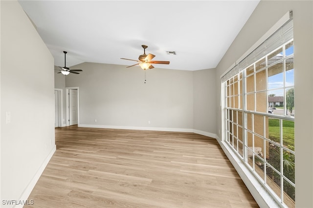 spare room featuring lofted ceiling, light wood-type flooring, and ceiling fan