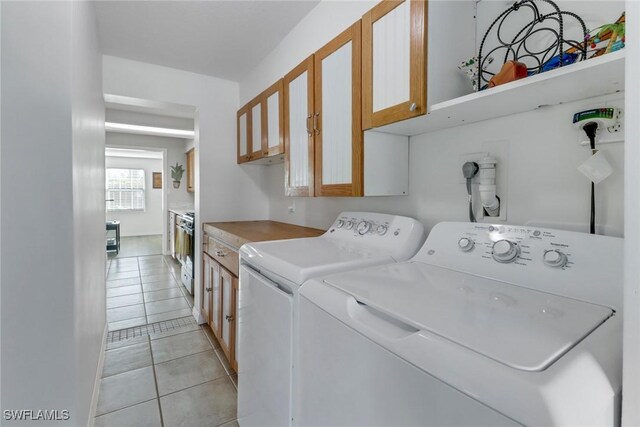 laundry room featuring separate washer and dryer, light tile patterned floors, and cabinets