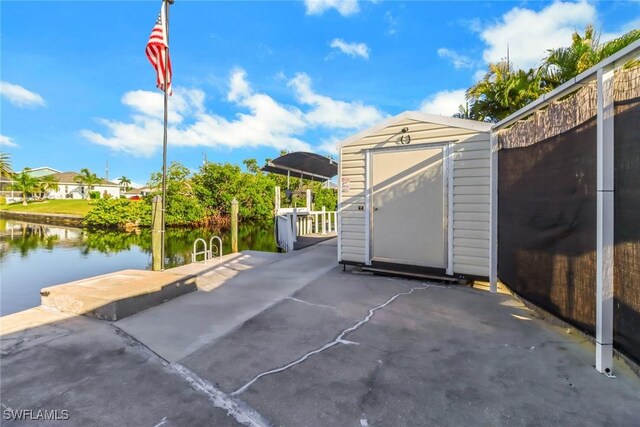 view of patio featuring a shed, a dock, and a water view