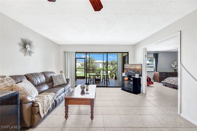 living room featuring ceiling fan, a textured ceiling, light tile patterned floors, and a healthy amount of sunlight