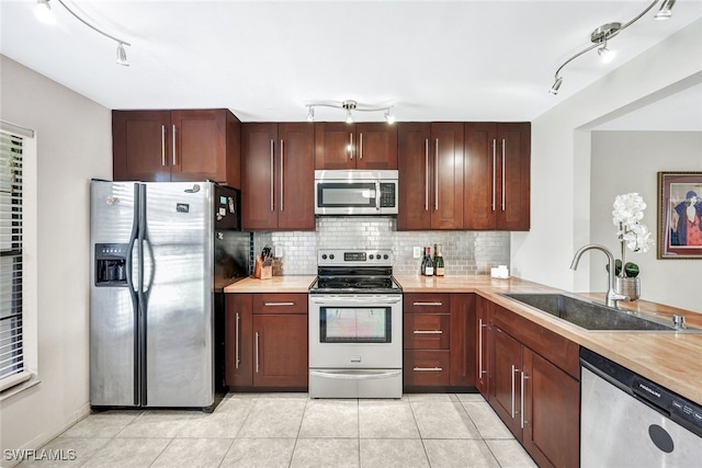 kitchen with light tile patterned floors, appliances with stainless steel finishes, backsplash, and sink