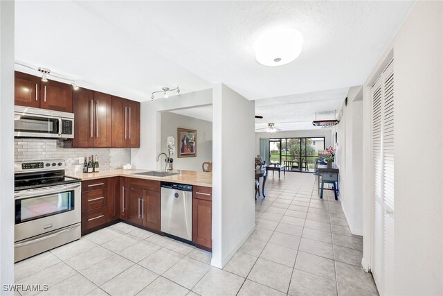 kitchen with appliances with stainless steel finishes, decorative backsplash, sink, ceiling fan, and light tile patterned floors