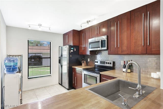 kitchen featuring light tile patterned floors, stainless steel appliances, decorative backsplash, and sink