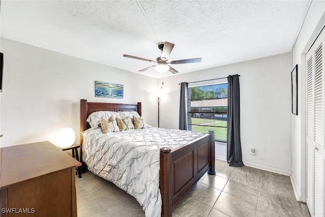 bedroom with ceiling fan, a textured ceiling, light tile patterned floors, and a closet