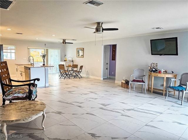 living room featuring ceiling fan, crown molding, and sink