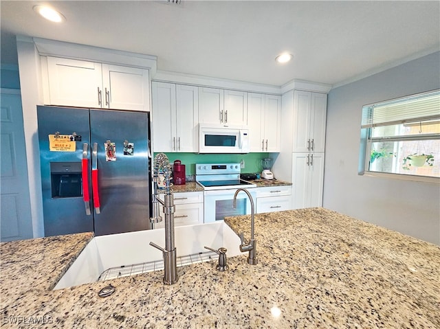 kitchen featuring light stone countertops, sink, white appliances, and white cabinetry