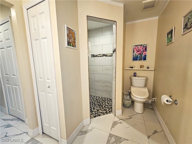 bathroom featuring toilet, crown molding, and a tile shower