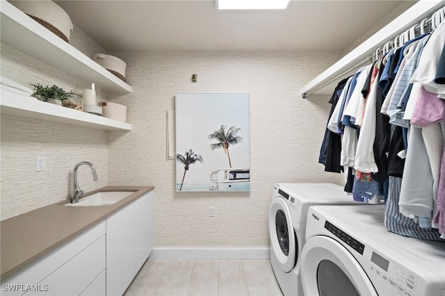 clothes washing area featuring separate washer and dryer, sink, and cabinets