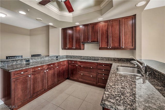 kitchen featuring a raised ceiling, sink, black stovetop, dark stone countertops, and kitchen peninsula