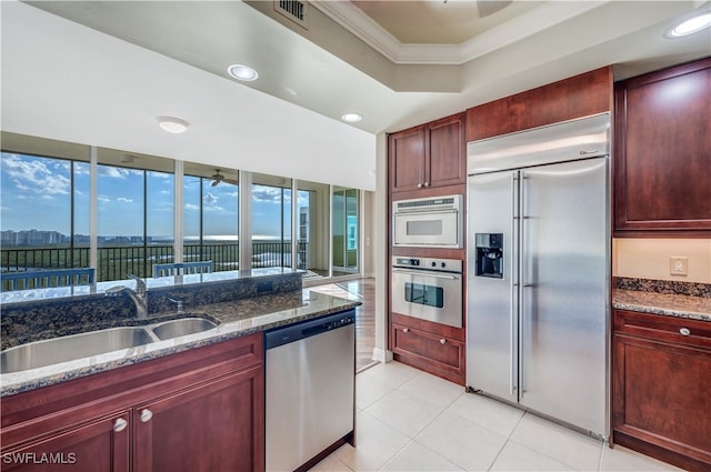 kitchen with light tile patterned floors, sink, appliances with stainless steel finishes, and dark stone counters