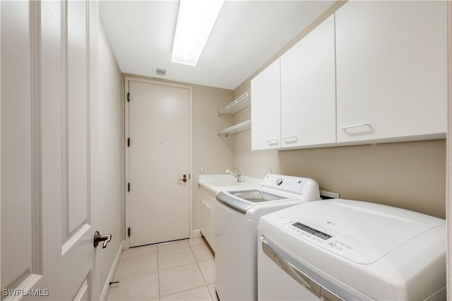 laundry room with cabinets, light tile patterned floors, washer and clothes dryer, and sink