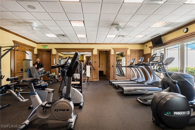 gym with a paneled ceiling, ceiling fan, and crown molding