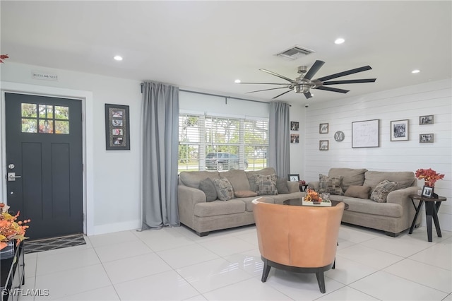 living room featuring wood walls, light tile patterned floors, and ceiling fan