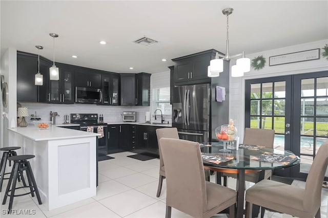 kitchen featuring appliances with stainless steel finishes, french doors, kitchen peninsula, pendant lighting, and decorative backsplash